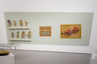 Ausstellungsansicht, Ausstellungsplakat Niederländisch-Indische-Kunstausstellung 1906 im Dialog mit acht Wajang-Figuren, die über diese Ausstellung in die Sammlung des Kaiser Willhelm Museums gelangten, Foto: Dirk Rose