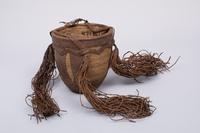 Vessel  
Container in pumpkin shape, leather, raffia, tassels  
H 21 cm (without tassels), W 20 cm  
Geographical attribution: Sudan  
DM VI 26
Object description  
Flowerpot-like container made of fine raffia and leather, the richly decorated leatherwork, especially the four hanging leather tassels make it easy to identify the container, conspicuous on the right and on the left are three wide leather stripes running from top to bottom, the upper rim is finished with a zig-zag leatherwork and above it a wider leather braiding, two braided leatherworks, from which the tassels hang, form a hanging device. 
Provenance  
Kunstmuseen Krefeld (since 1923); Deutsches Museum für Kunst in Handel und Gewerbe (until 1923); previous owner (unknown); transfer to Germany (unknown); appropriation in region of origin (unknown); manufacture (unknown).
Object History  
Hagen-born art patron Karl Ernst Osthaus founded the German Museum of Art in Trade and Commerce in 1909 with the support of the Deutscher Werkbund. With the museum, Osthaus pursued the goal of achieving an aesthetic imprint on industrial product design by creating and lending exemplary decorative arts. To this end, the museum lent traveling exhibitions to interested institutions in German-speaking countries and beyond. In 1911, an exhibition on "exotic wickerwork", which was also promoted as "examples of good craftsmanship", was added to the program